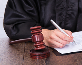 Close-up Of A Judge Hitting Mallet At Desk